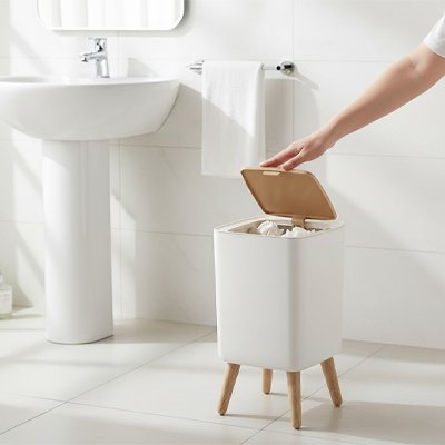 Poubelle salle de bain blanche avec couvercle en bois et pieds en bois.